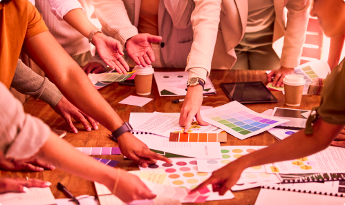 Group of people gathered around a desk choosing color palettes as part of branding marketing services